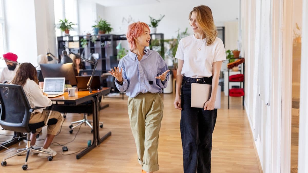 Due persone conversano in un ufficio, rappresentando collaborazione, inclusione e senso di appartenenza sul lavoro.