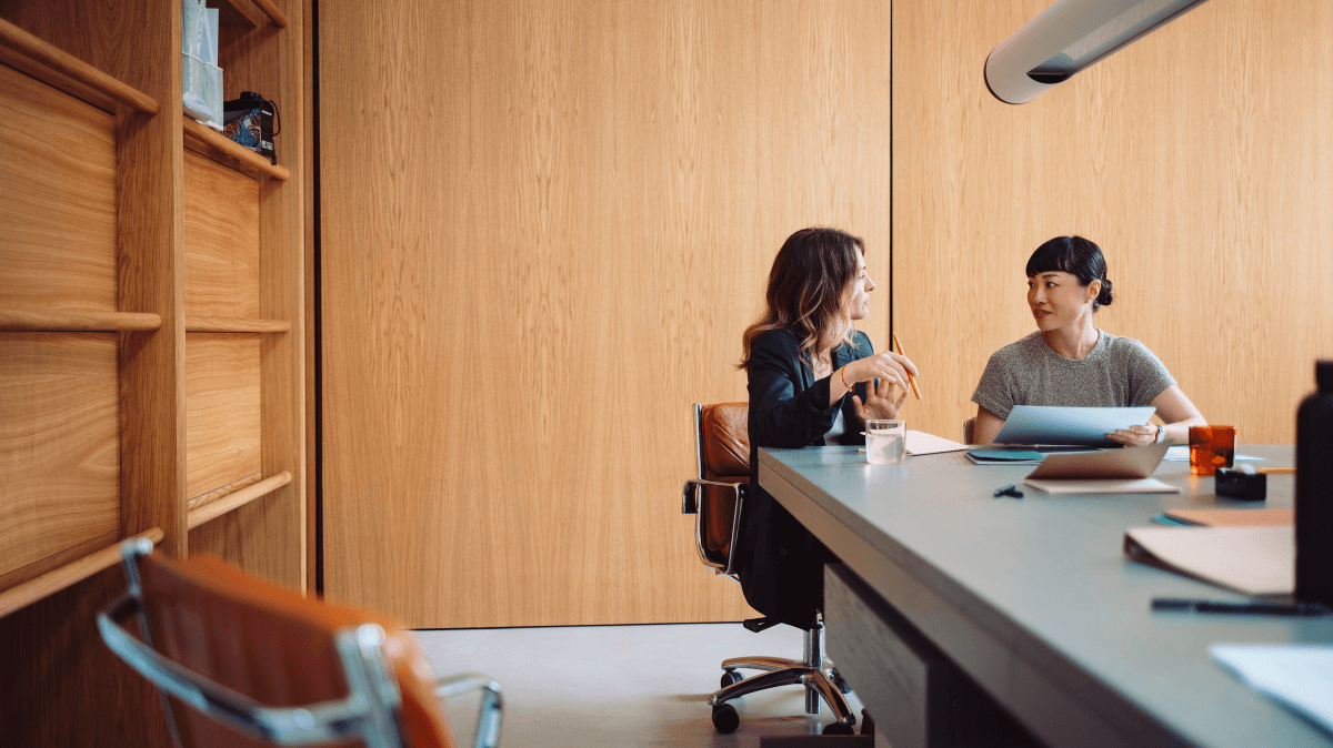 Due professionisti conversano in un contesto di lavoro, rappresentando coaching, mentoring e sviluppo professionale in azienda.