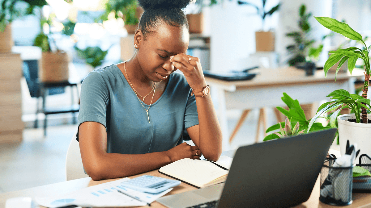 Professionista seduta alla scrivania in un momento di stanchezza, rappresentando burnout, stress lavorativo e benessere mentale al lavoro.