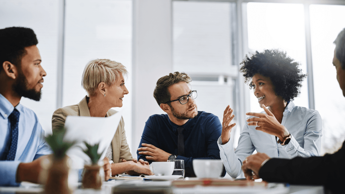 Equipo de profesionales conversa en una reunión de trabajo, representando colaboración, escucha y prevención de riesgos psicosociales.